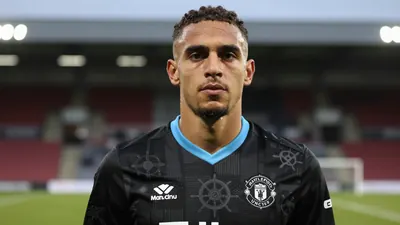 A photorealistic image of an anonymous Hartlepool United player wearing the new away strip, with a black base and tonal...
